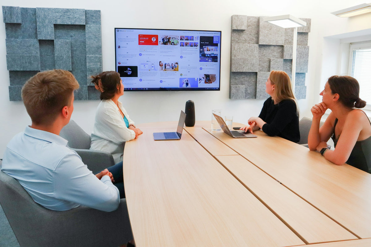 Team in a meeting room looking at a wall screen