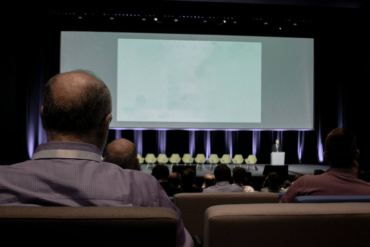Audience in a venue watching a large screen